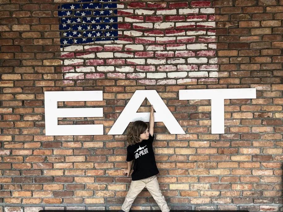 Boy in front of EAT sign