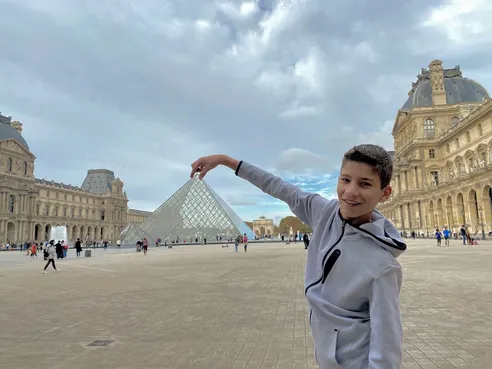 Boy in Louvre forced perspective with pyramid